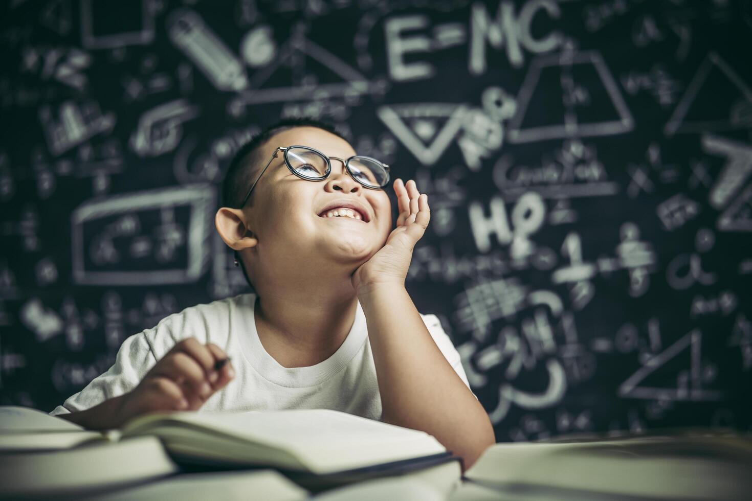 A boy with glasses man writing in the classroom photo