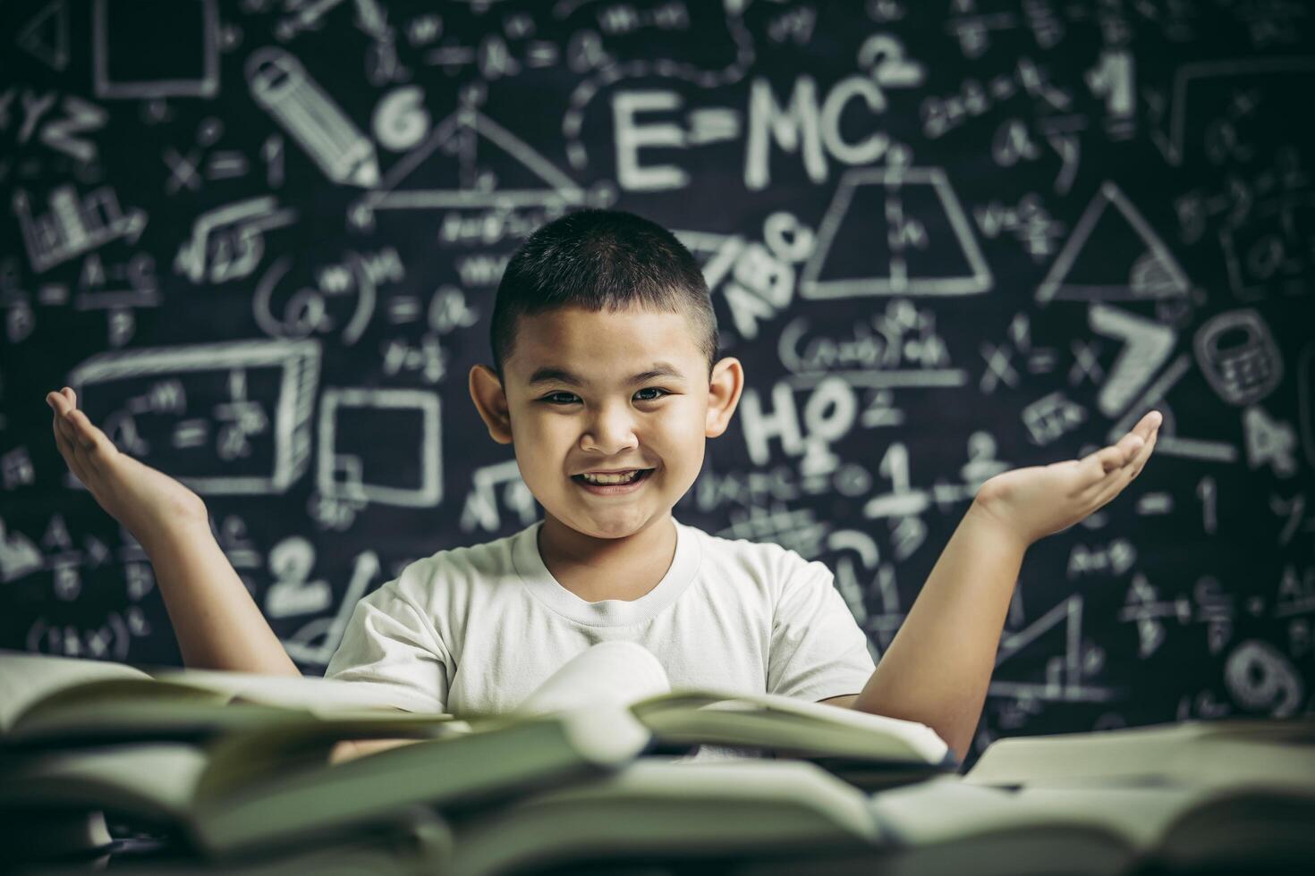 A boy sitting in the classroom reading a book photo