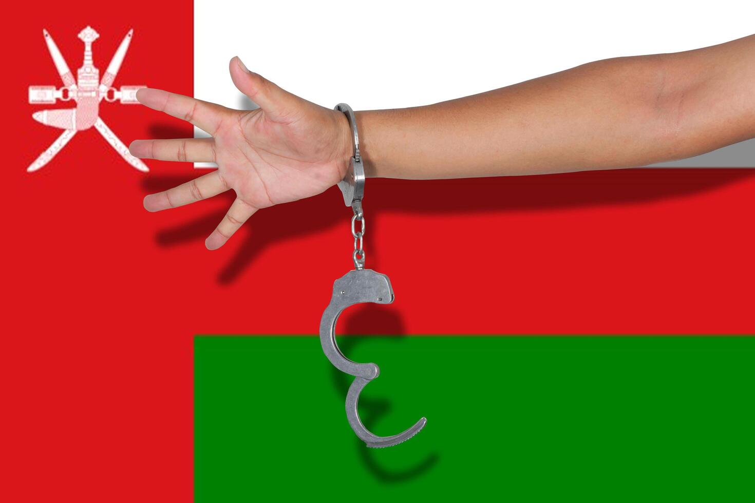 handcuffs with hand on Oman flag photo