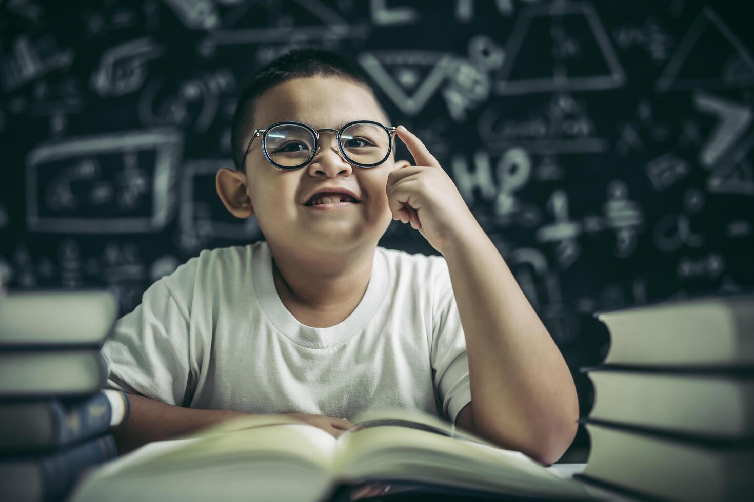 Los niños con gafas escriben libros y piensan en el aula. foto