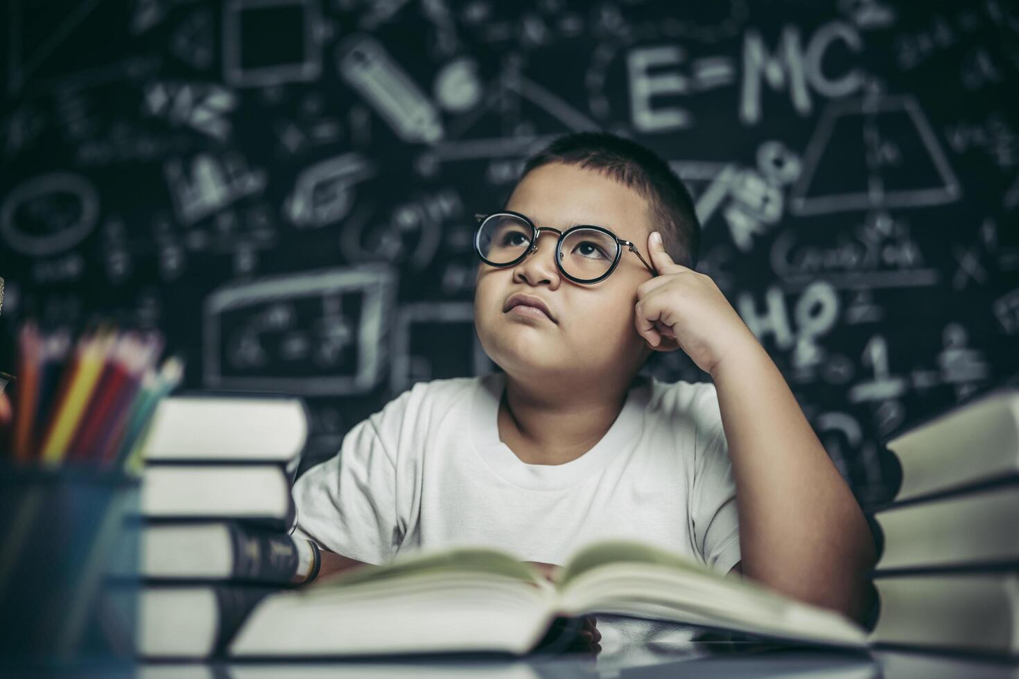 Los niños con gafas escriben libros y piensan en el aula. foto