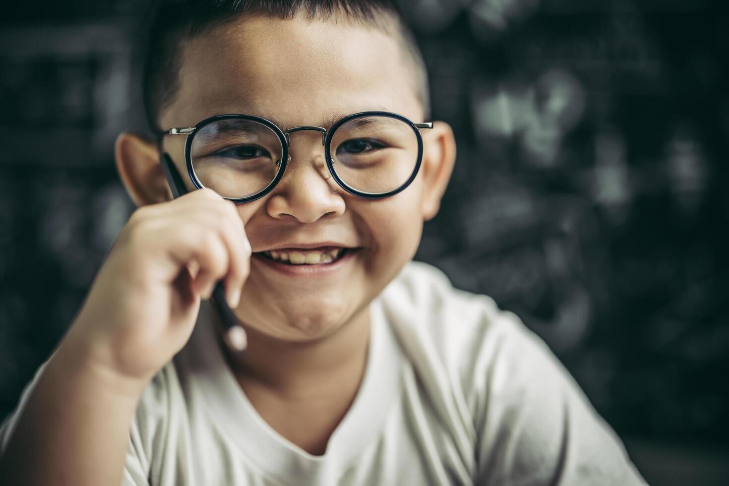 niño con gafas sentado en el aula estudiando foto