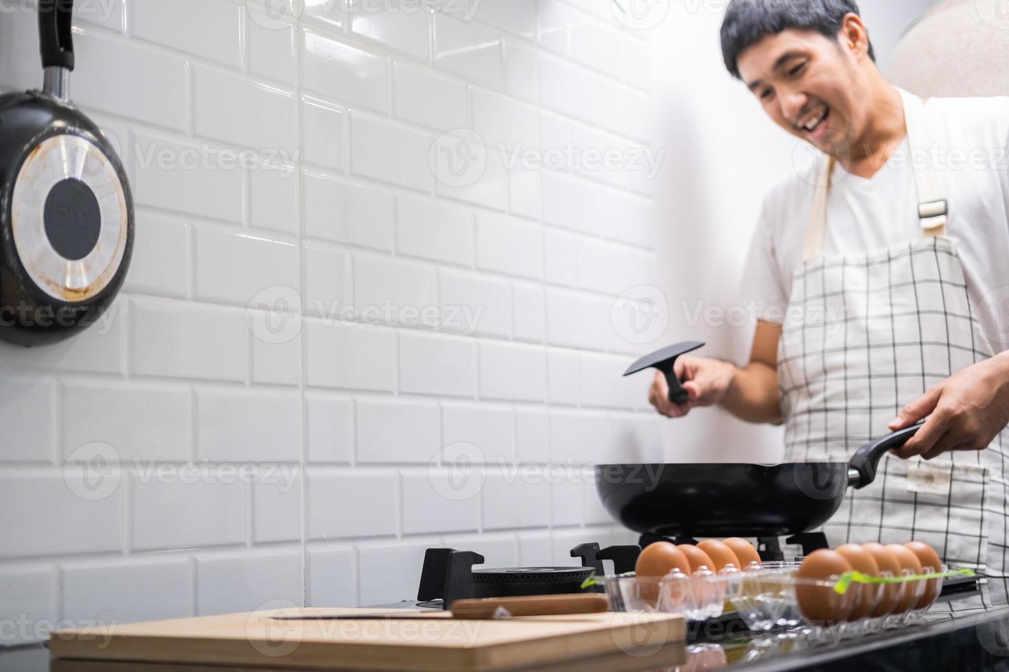 Chef asiático huevos fritos en una sartén a la comida tailandesa en la cocina en la estufa de gas el aceite en la sartén hirviendo. Huevos y cerdo cocidos. antes de servir a la familia feliz para comer juntos en casa foto