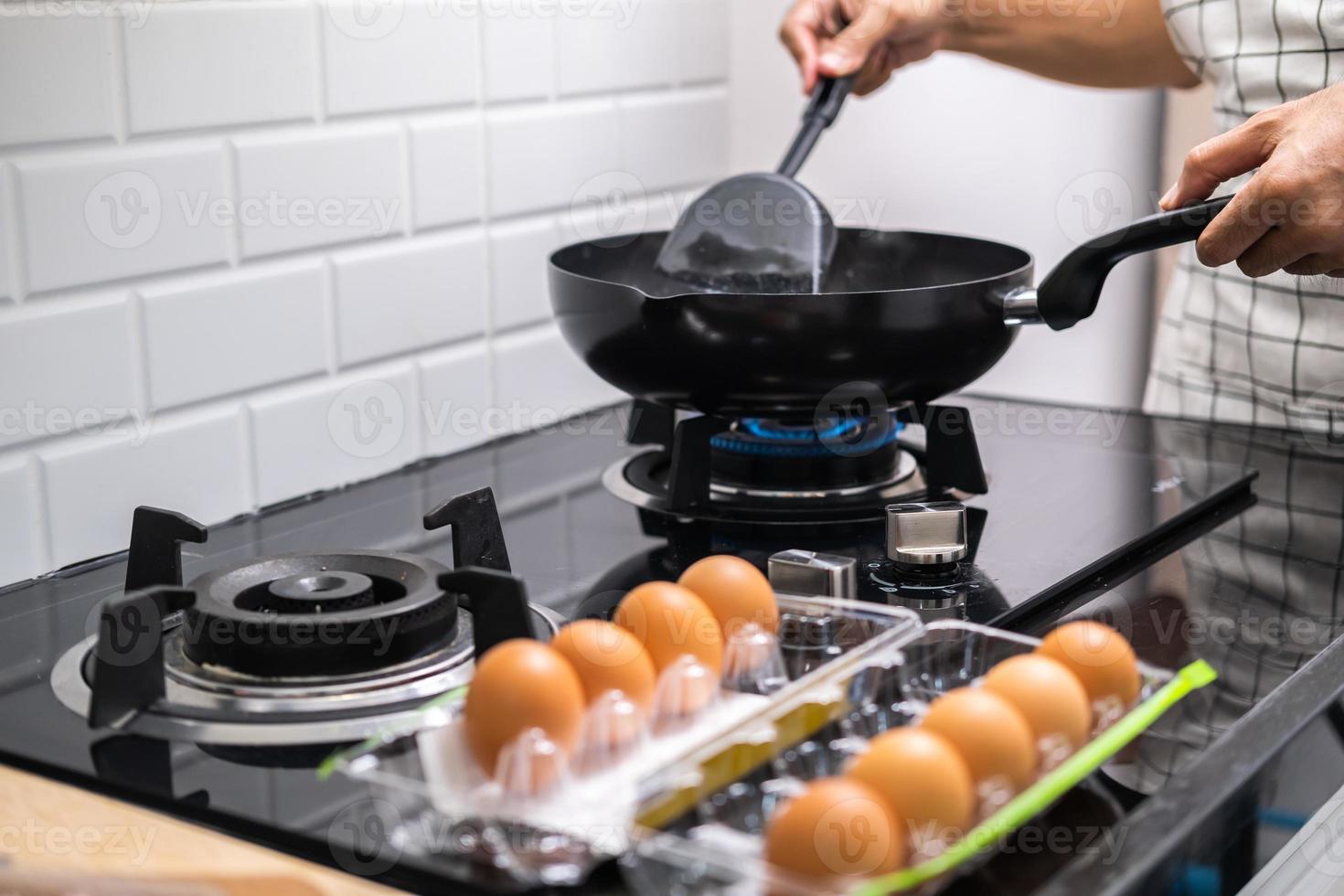 Chef asiático huevos fritos en una sartén a la comida tailandesa en la cocina en la estufa de gas el aceite en la sartén hirviendo. Huevos y cerdo cocidos. antes de servir a la familia feliz para comer juntos en casa foto