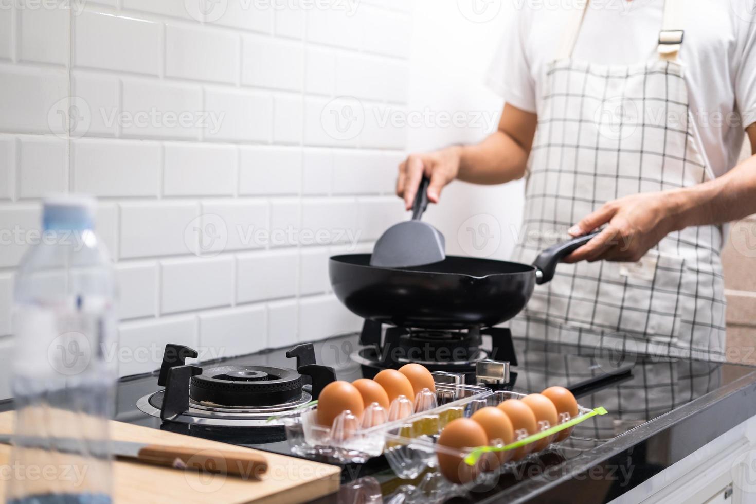 Chef asiático huevos fritos en una sartén a la comida tailandesa en la cocina en la estufa de gas el aceite en la sartén hirviendo. Huevos y cerdo cocidos. antes de servir a la familia feliz para comer juntos en casa foto