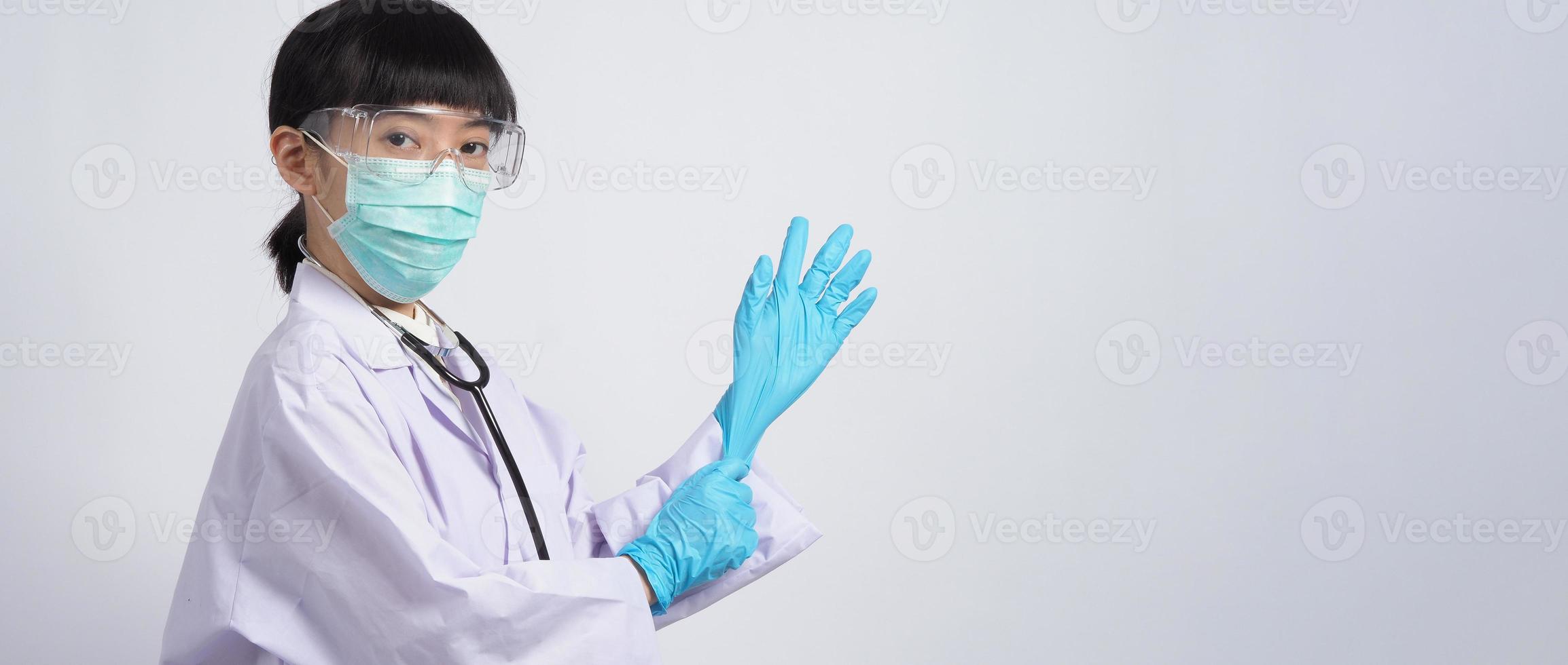 usando guantes. El médico asiático usa guantes de manos de nitrilo de goma azul. foto