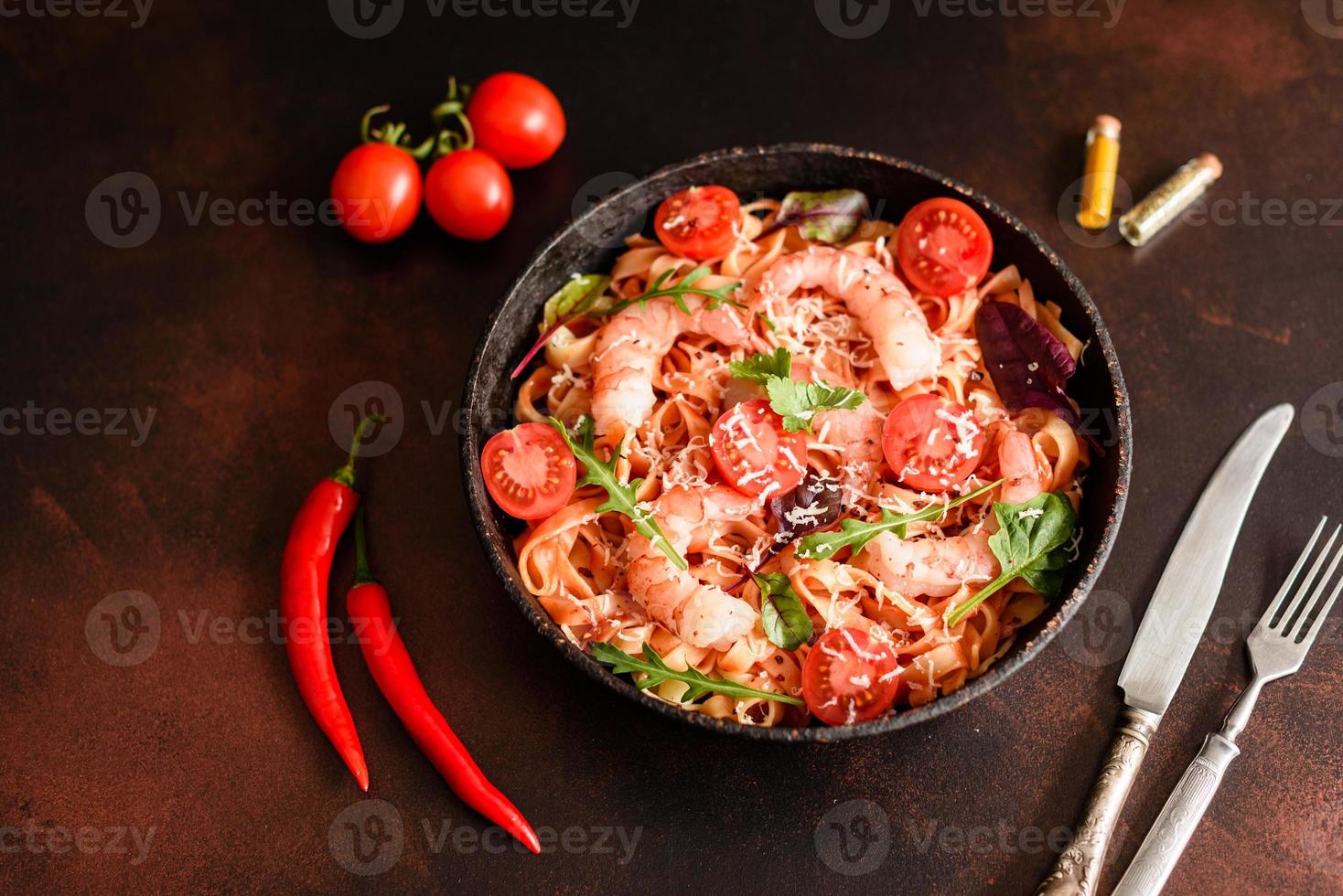 Sabrosa pasta con camarones y tomate en una sartén foto
