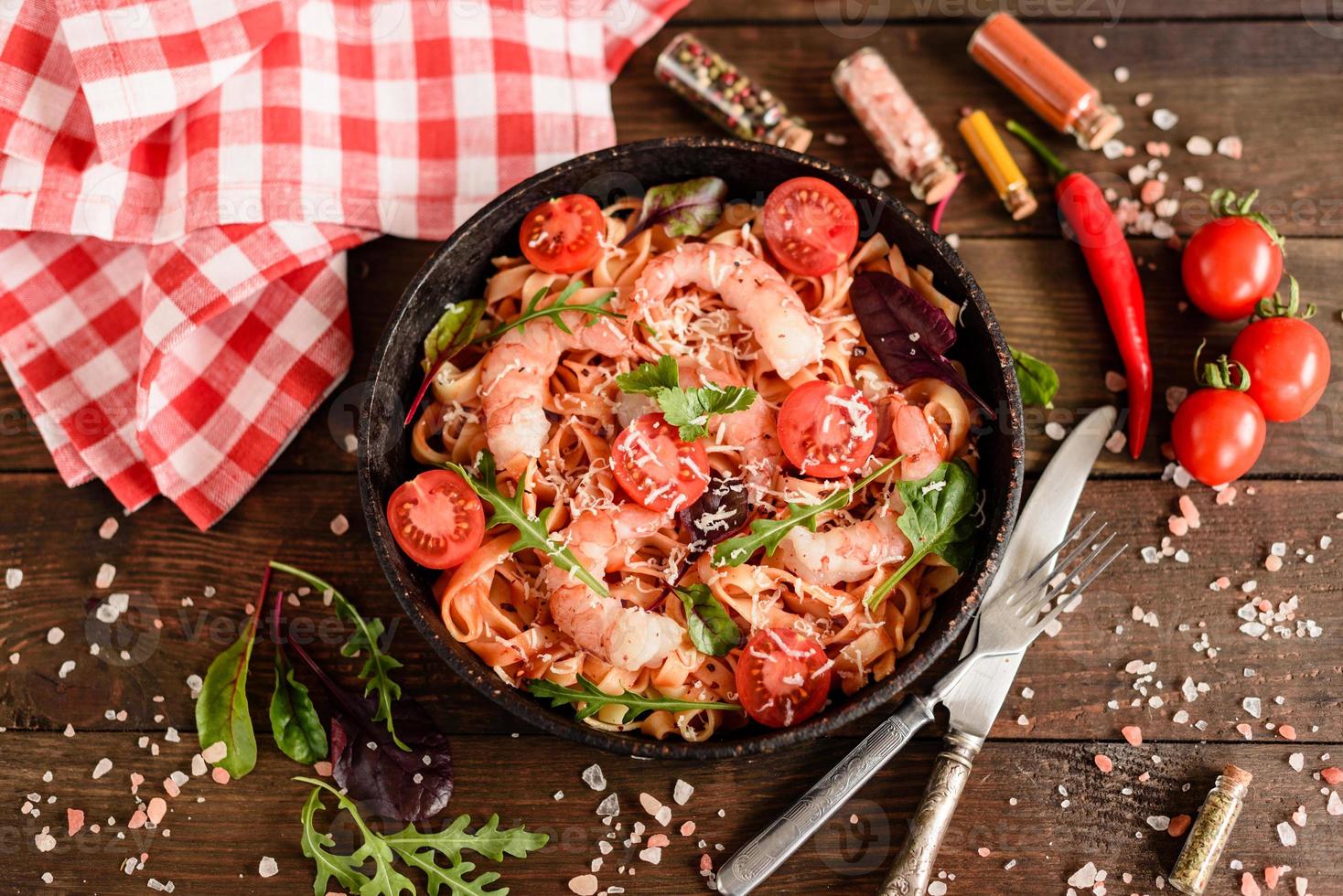 Sabrosa pasta con camarones y tomate en una sartén foto