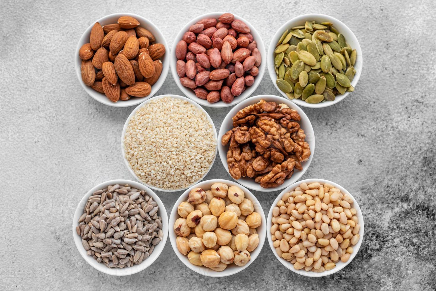 Assortment of nuts in white saucers on a concrete background photo