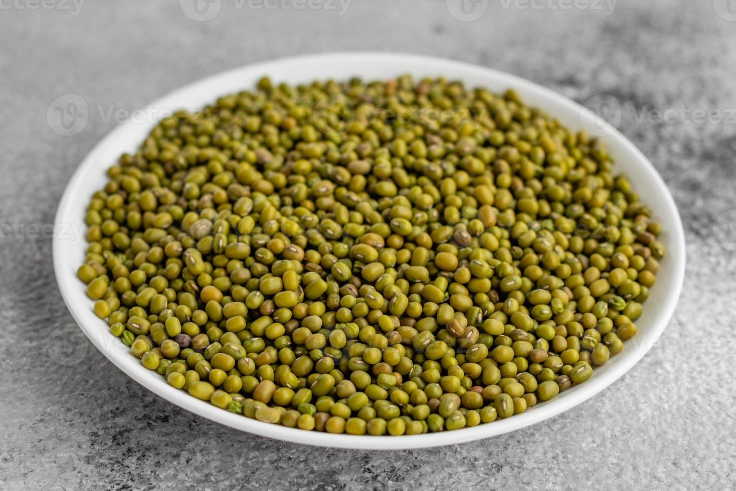 Lentil in a white saucer on a gray concrete background photo