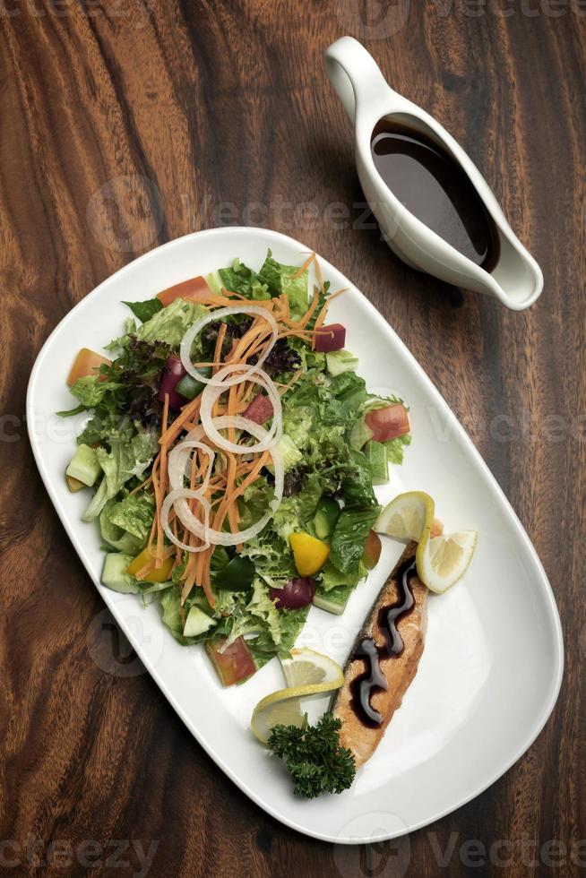 Ensalada orgánica mixta de verduras con filete de salmón y vinagreta balsámica foto