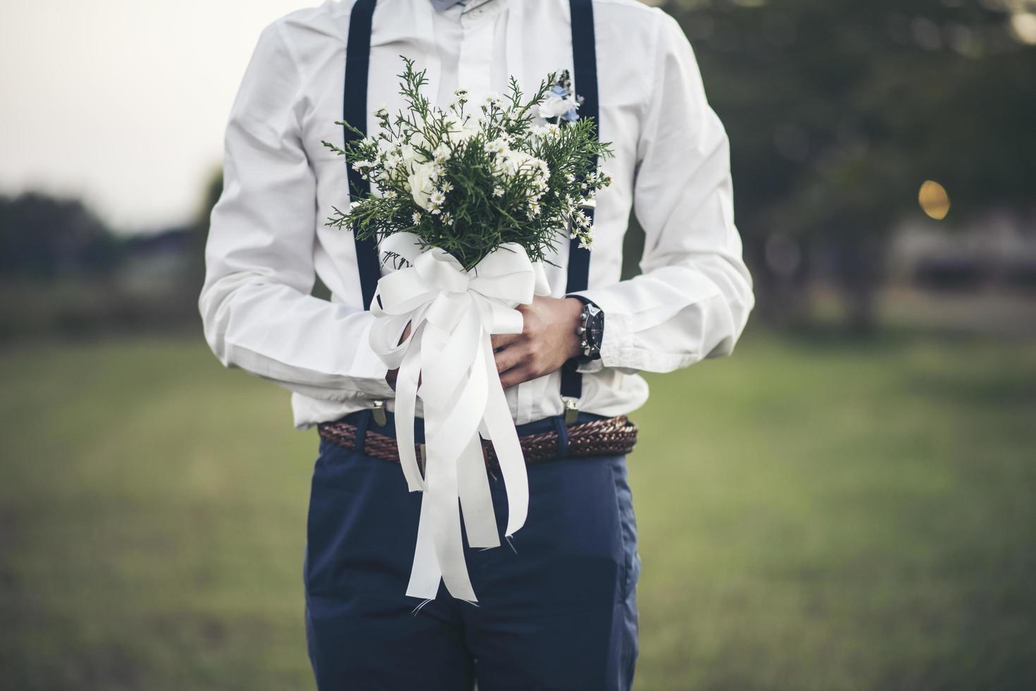 mano del novio sosteniendo la flor del amor en el día de la boda foto