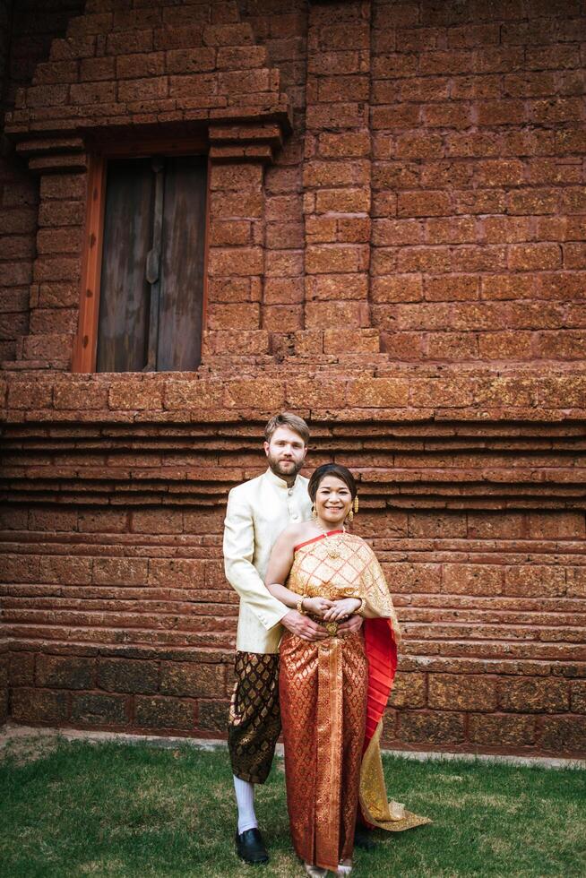 La novia asiática y el novio caucásico tienen tiempo romántico con el vestido de Tailandia foto