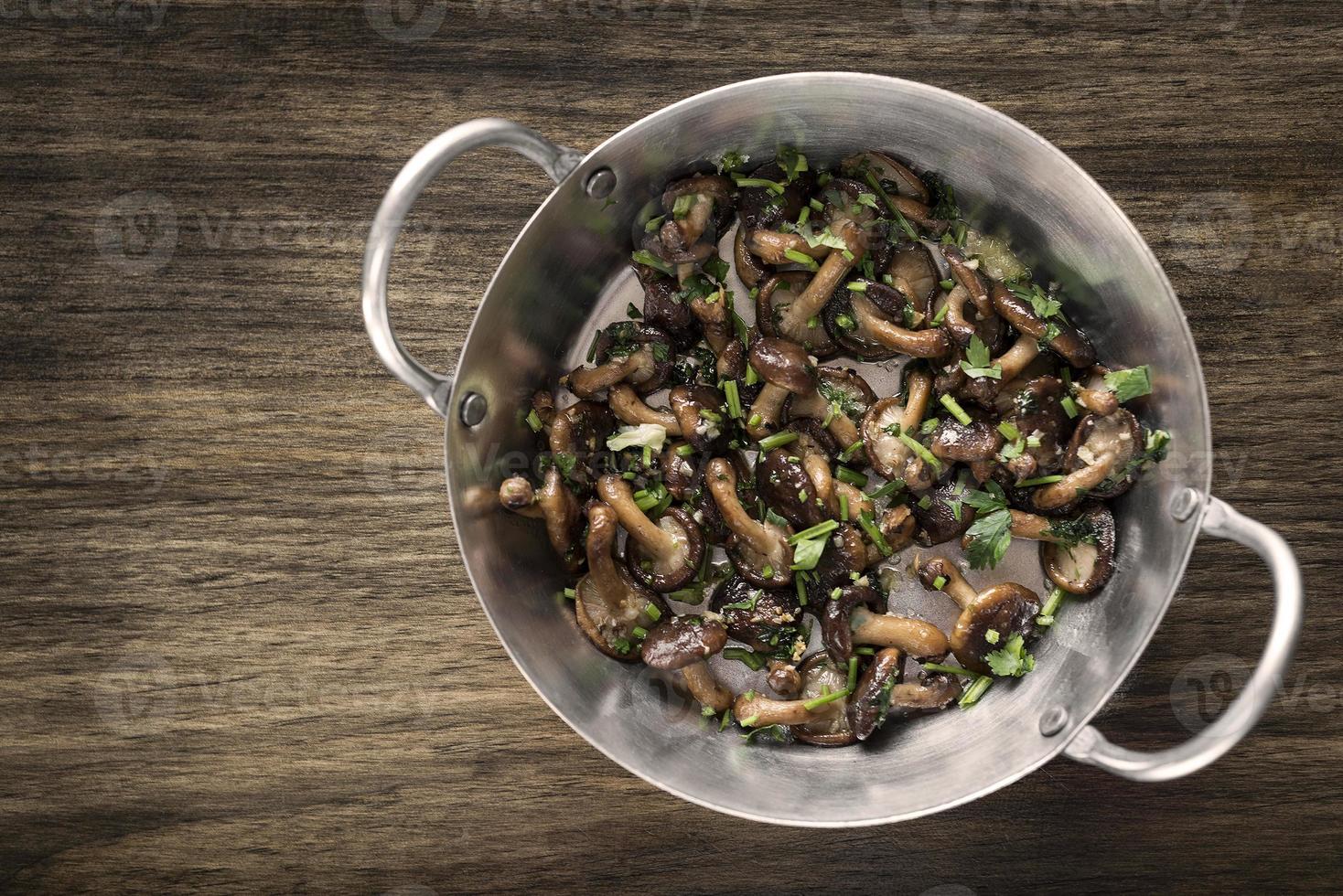 Shiitake mushrooms sauteed with garlic and herbs in metal pan photo