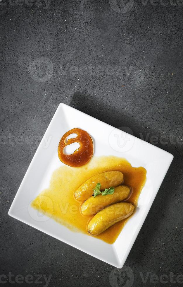 Plátano frito flambeado en reducción de naranja y caramelo de mandarina foto