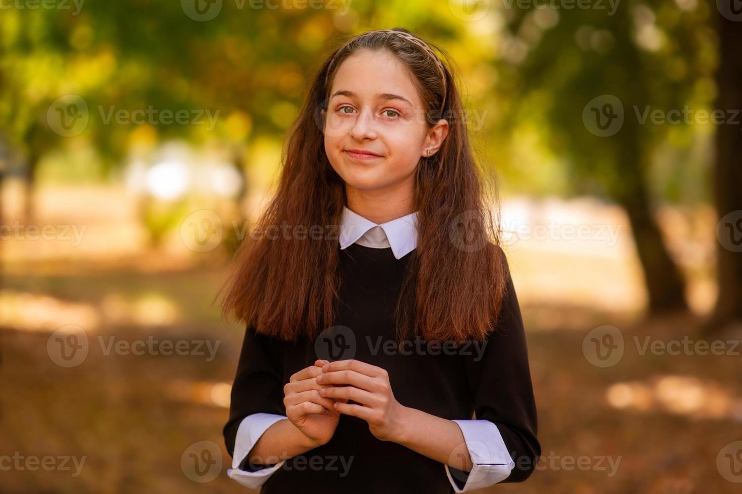 School concept. Little girl 11 or 12 years old in a dress on the background of nature in autumn. photo