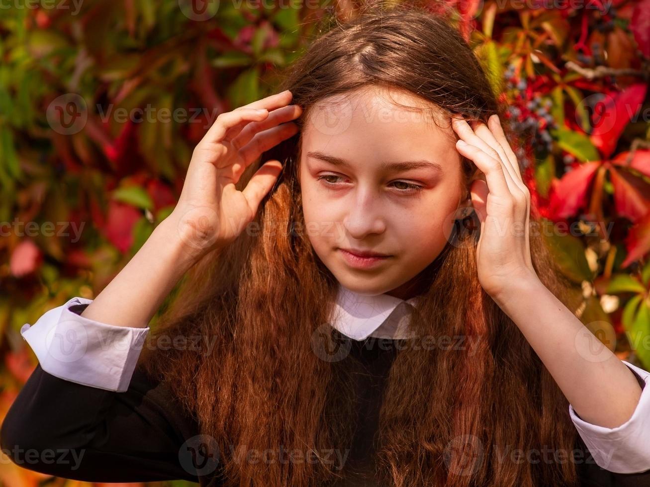 Schoolgirl in school clothes in nature on a background of autumn leaves. Girl 11-12 years old. photo