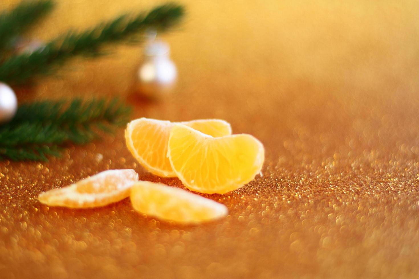 Peeled orange fresh mandarin and green fur Christmas tree on golden glitter background, New year card decoration, pine and citrus fruit photo