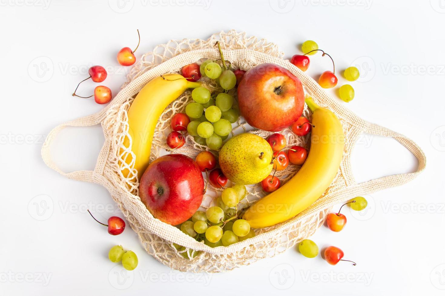 Organic ripe fruits in eco-friendly mesh bag on white background. Trendy string bag for shopping. Healthy eating and sustainable lifestyle concept. Zero waste. photo