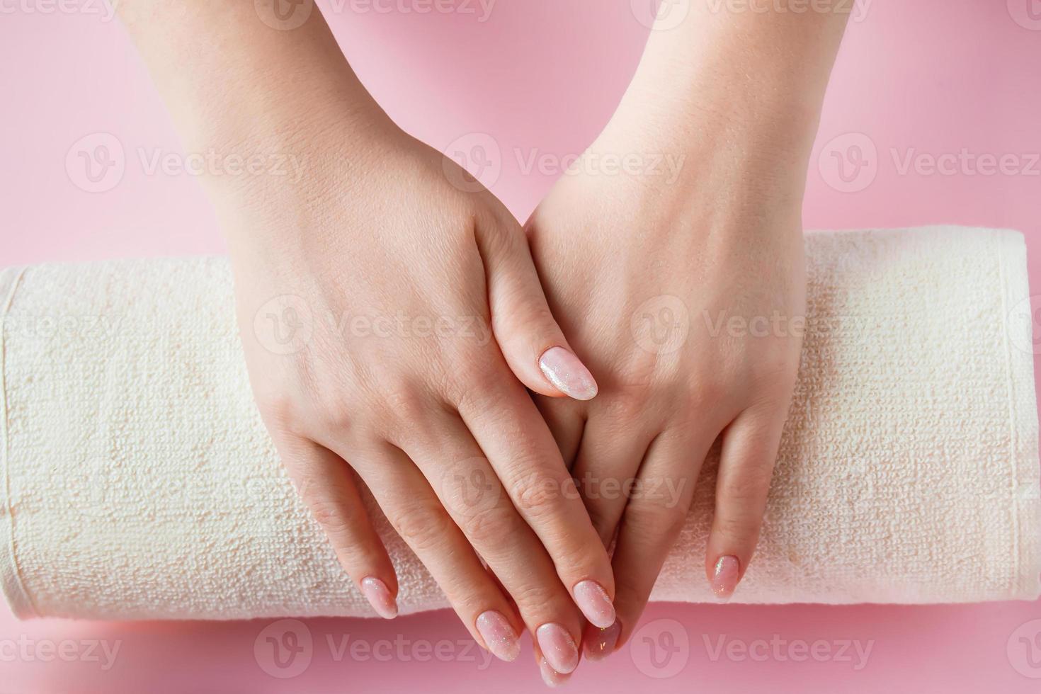 procedimiento de spa para el cuidado de las uñas en un salón de belleza. manos femeninas y herramientas para manicura sobre fondo rosa. concepto de cuidado corporal. foto