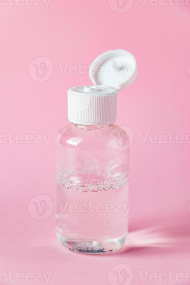 Bottle with micellar cleansing water on pink background. Skin care concept. photo