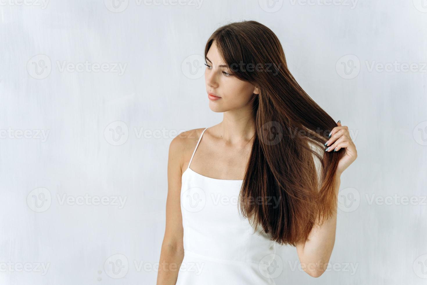 As free as wind. Portrait of charming cute woman is standing and looking away while enjoying of the quality of her long hair. Isolated background photo