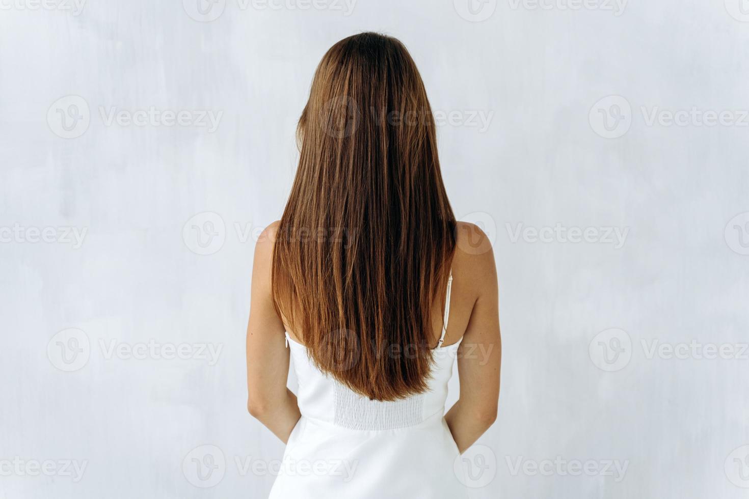 Beauty and hair care. Back view of young sensual brunette lady with voluminous hair posing isolated on white and showing her healthy hair. Stock photo