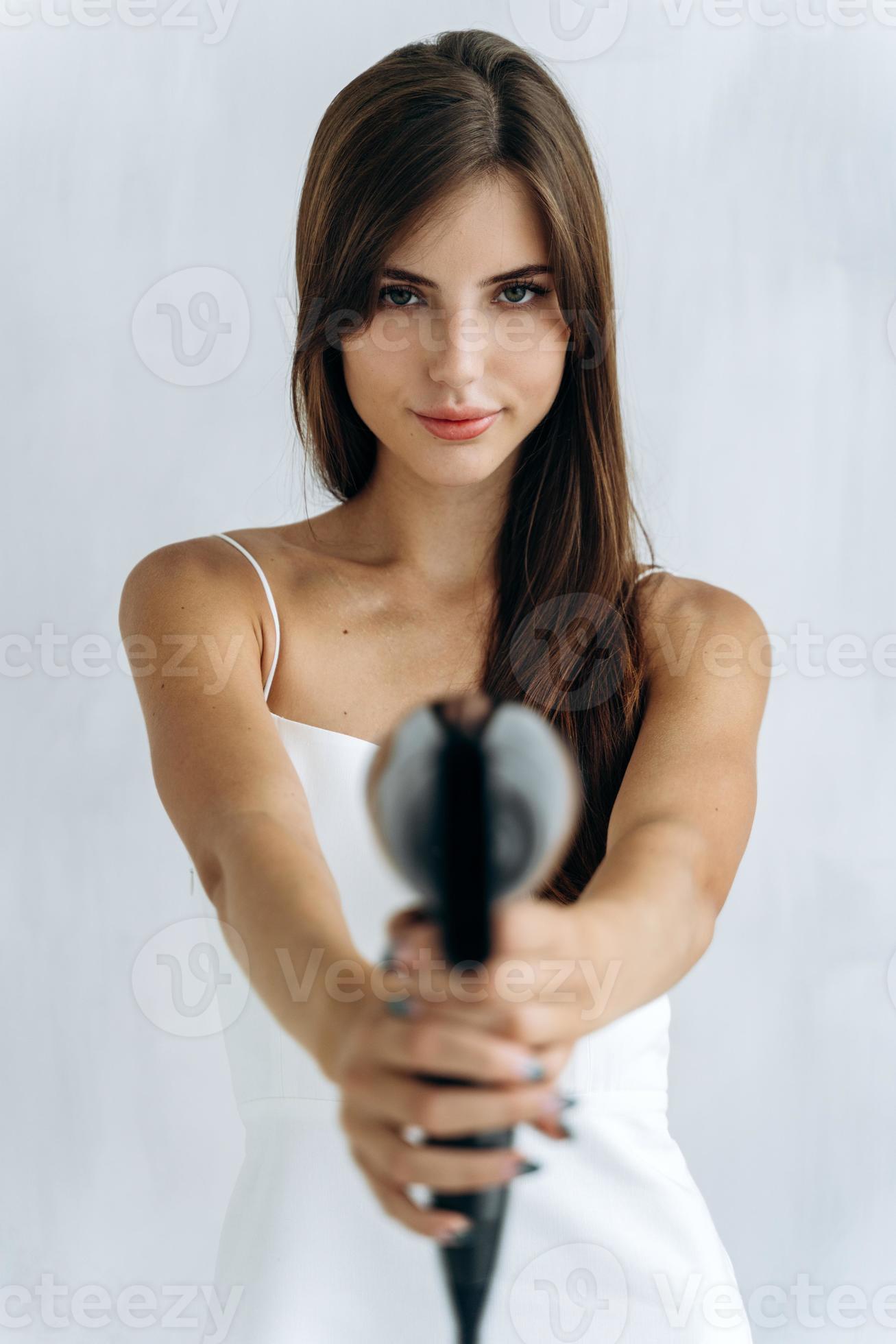 At gunpoint. Beautiful happy woman drying healthy long straight hair using  hair dryer. Portrait of attractive girl with brunette hair holding  hairdryer like a gun. Hairstyle and hairdressing concept 3490300 Stock Photo