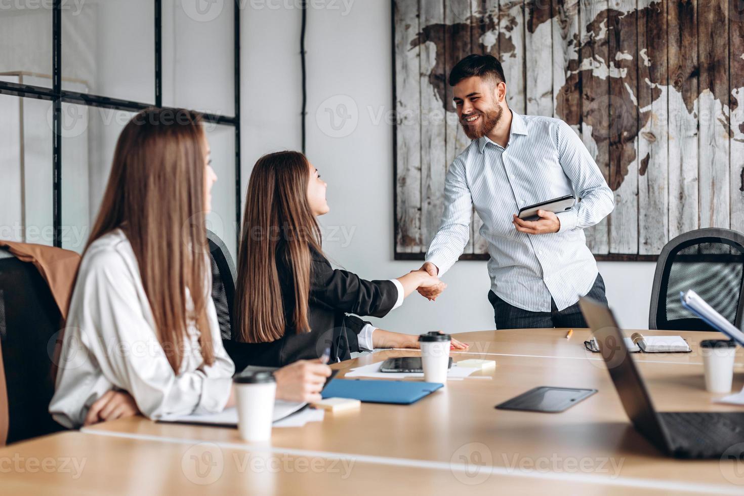 Attractive guy with a beard shakes hands with the girl he works with in the office photo