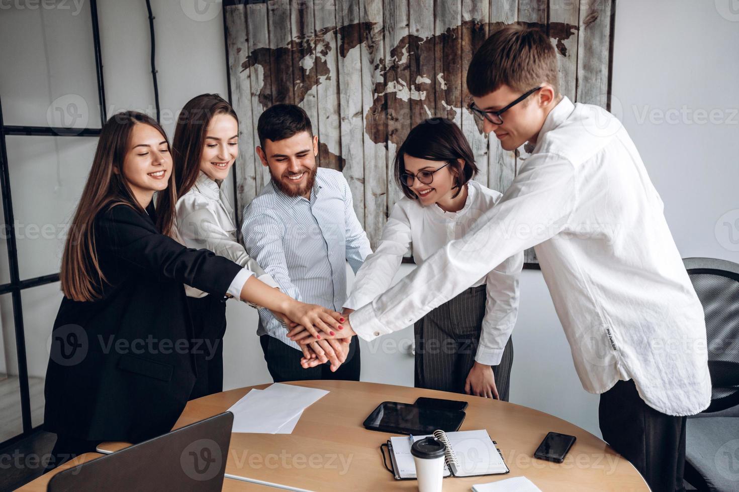 Working together. A friendly team of business people, putting their hands together, is one. photo