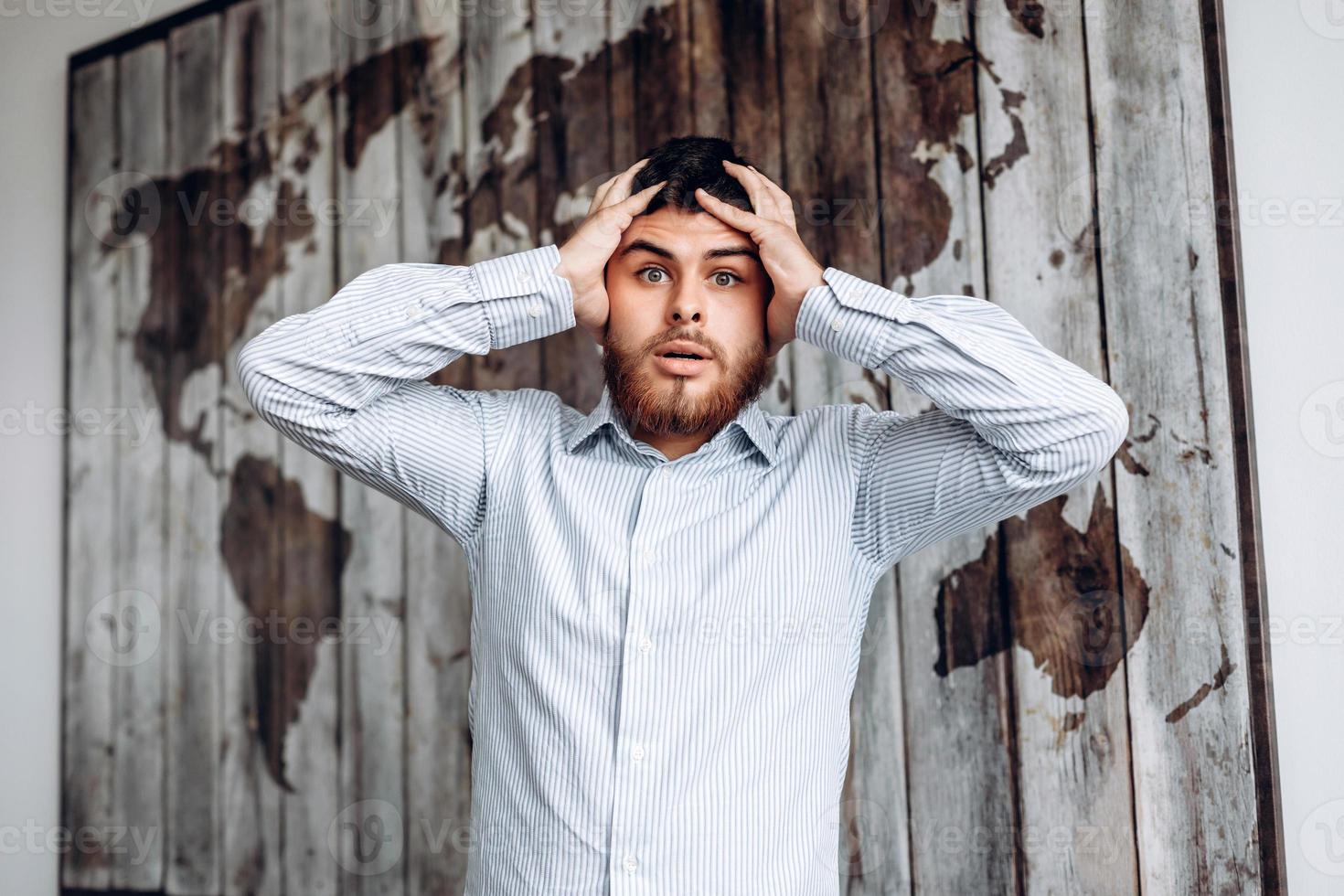 Portrait of a man with beard. He grabs his head in amazement, bulging his eyes and looking into the camera - Image photo