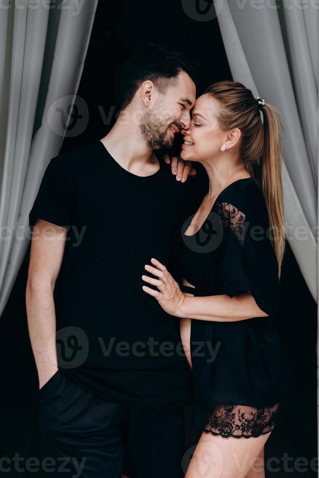 Feliz pareja esperando bebé posando sobre fondo oscuro, perfil foto