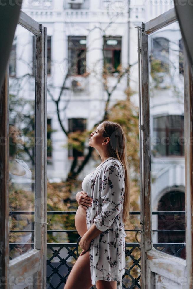 mujer embarazada en la terraza pensando en abrazar su barriga. feliz espera. foto