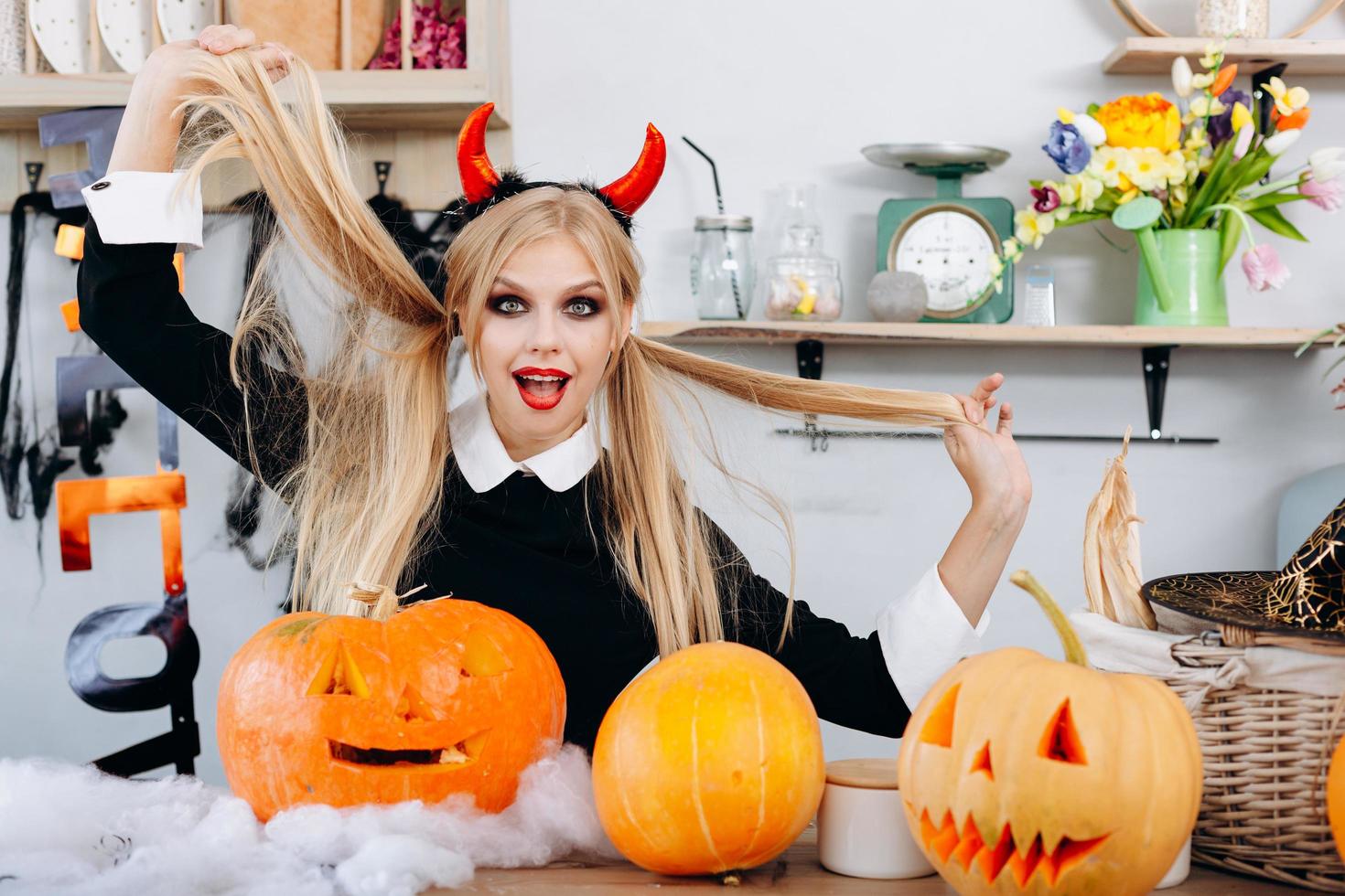 diablo divertido mujer sentada en la mesa junto a un tonto de calabazas.- concepto de halloween foto