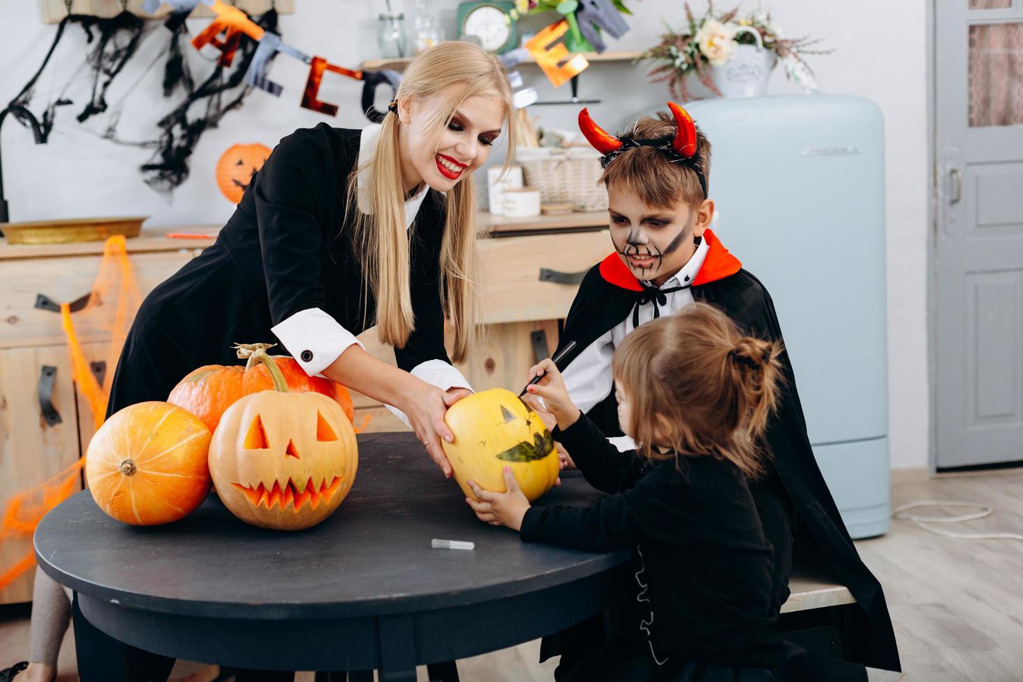 Mother and children drawing on pumpkin, play and  have funny time at home. -Halloween concept photo