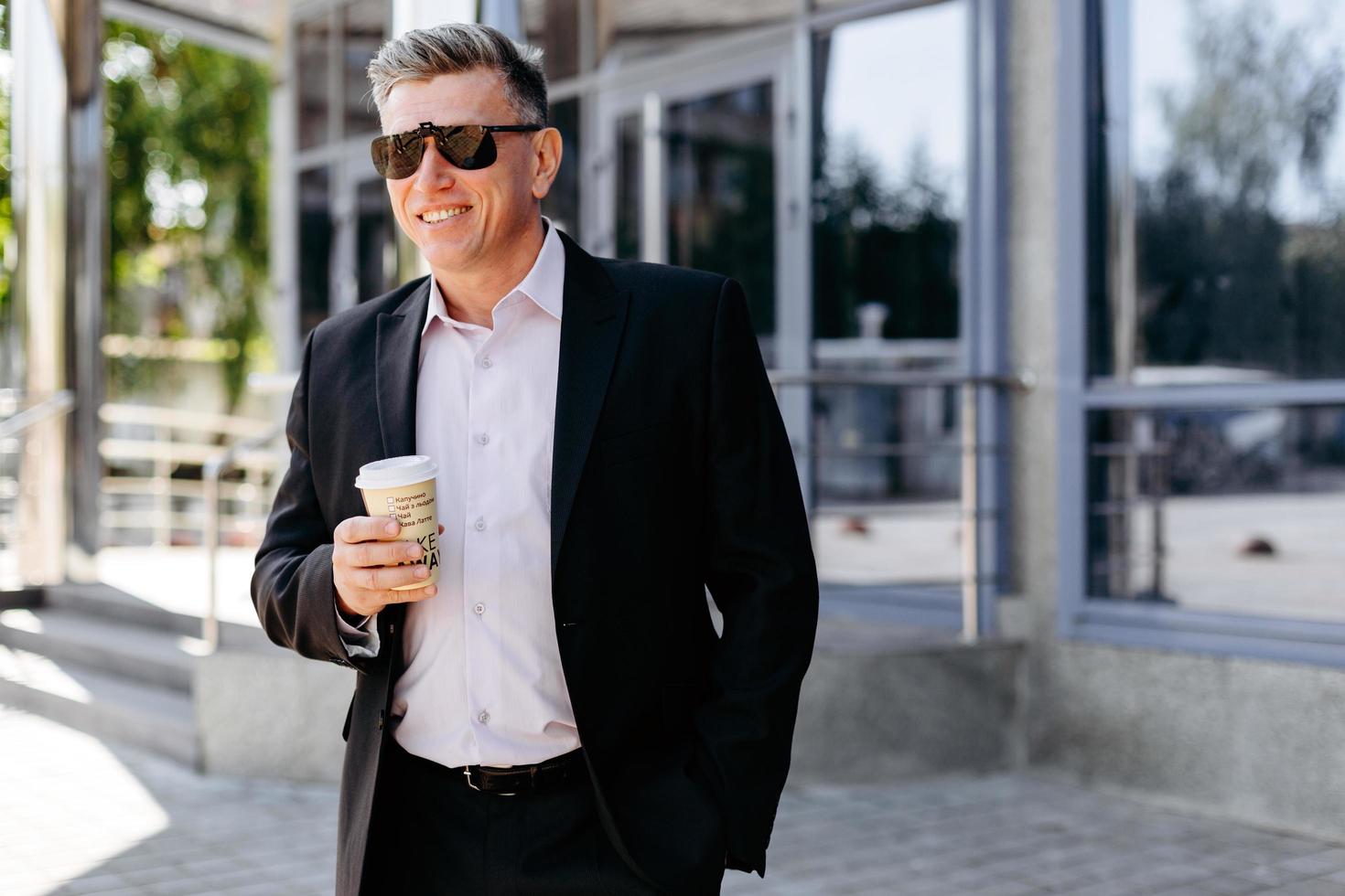 Retrato de hombre de negocios senior sosteniendo una taza de café y sonriendo. - imagen foto