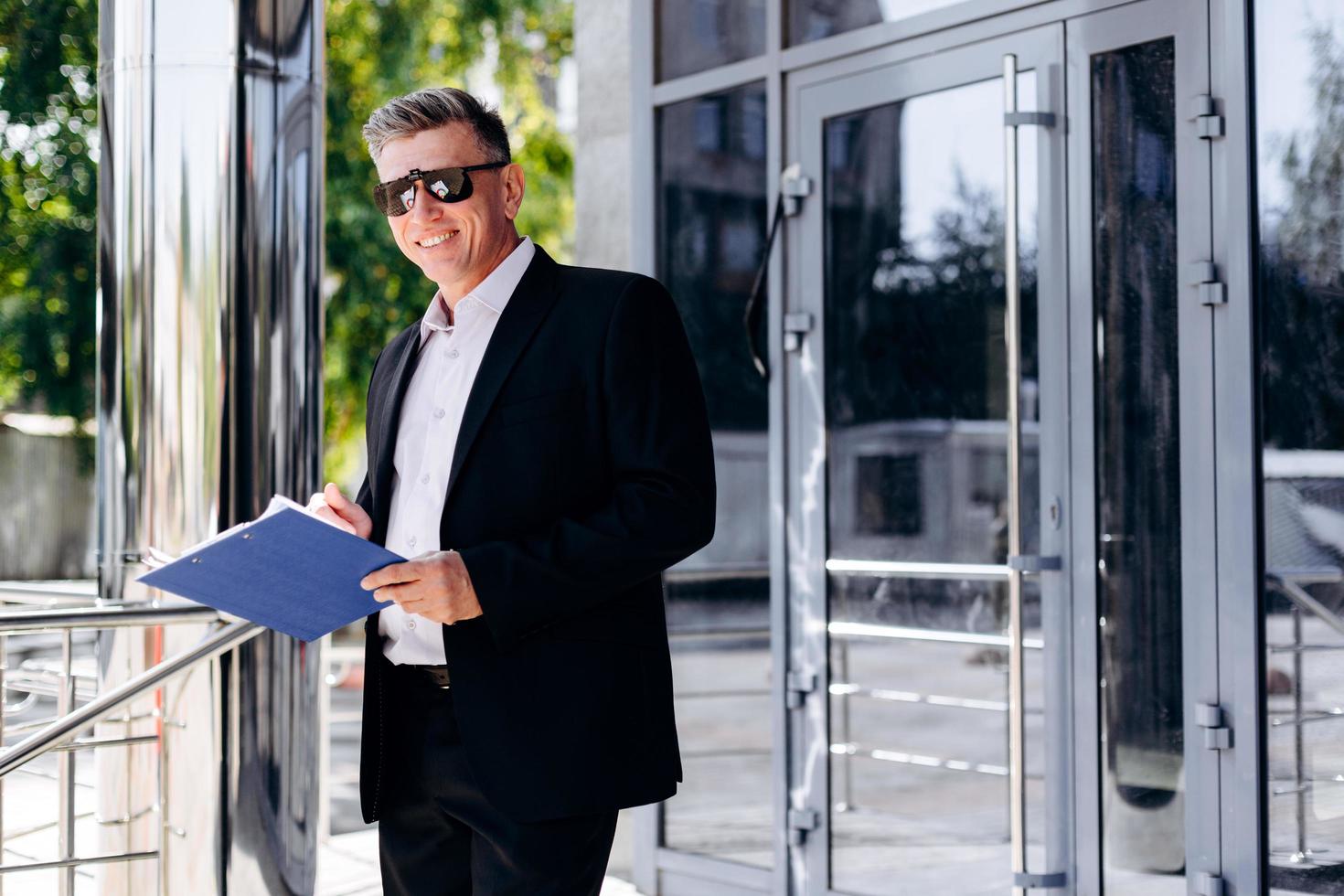 Retrato de hombre de negocios senior feliz en gafas de sol sosteniendo un documento. - imagen foto