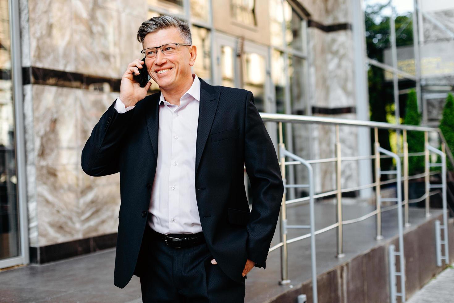 sonriente hombre de negocios senior hablando por teléfono móvil al aire libre. - imagen foto