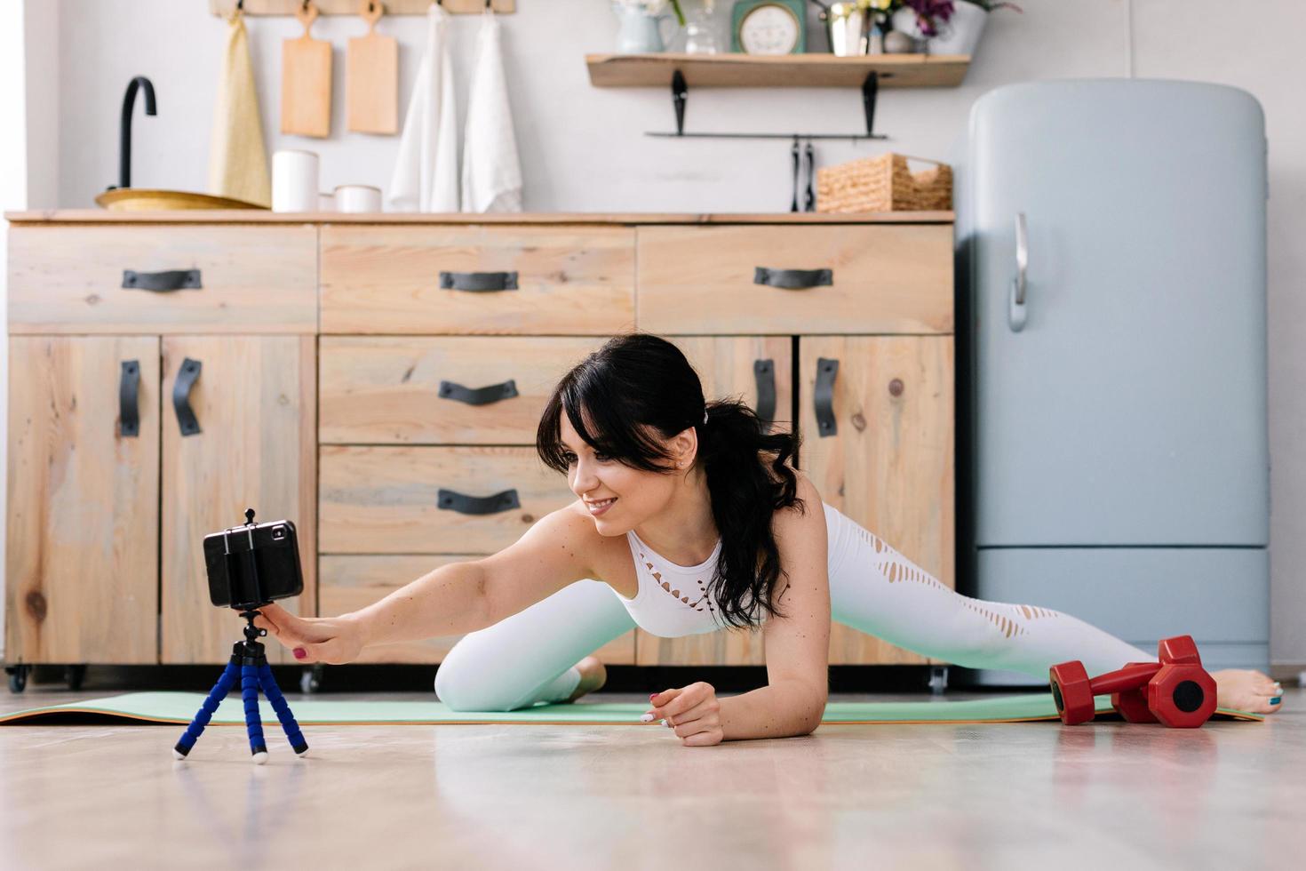 Young sportswoman doing leg stretches on a sports rug photo