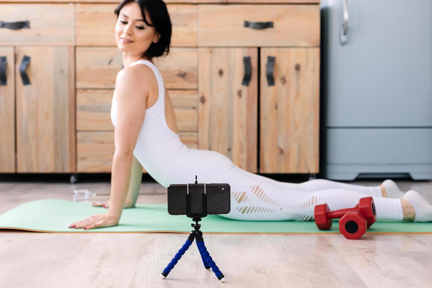 Attractive young fitness woman wearing sportswear doing stretching exercises, using fitness mat photo