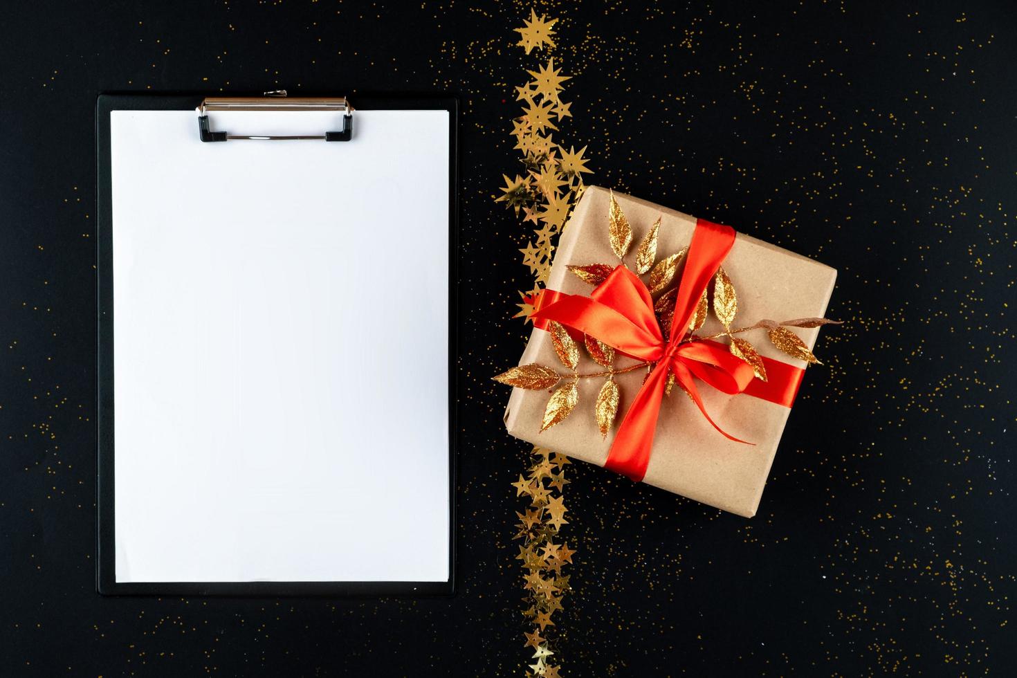 Christmas wish list with empty space for text on black background with golden star and gift. photo