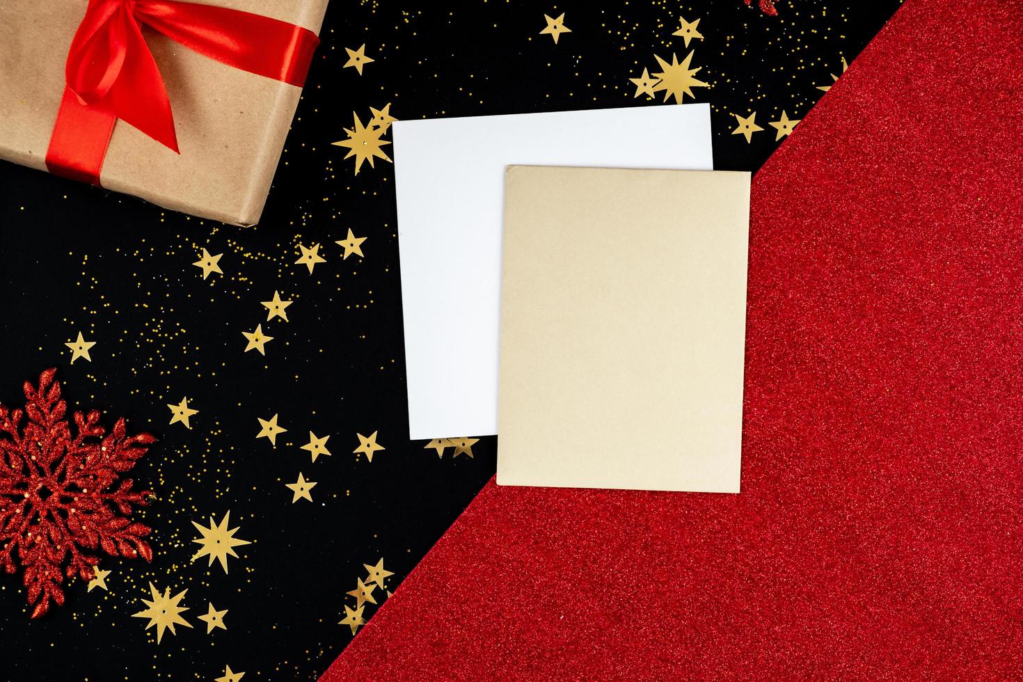 sobre un fondo festivo, rojo-negro, de año nuevo hay tarjetas de felicitación y un regalo foto