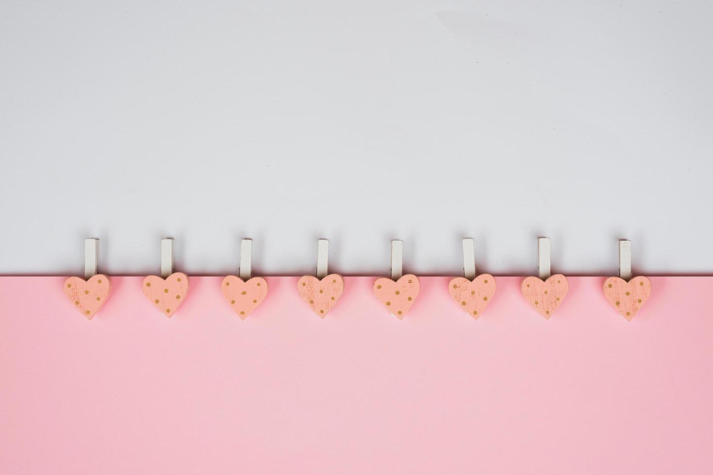 Background for Valentine's Day holiday. Pink hearts and clothespins on a delicate pink and white background. Valentines day concept. Top view, flat lay photo