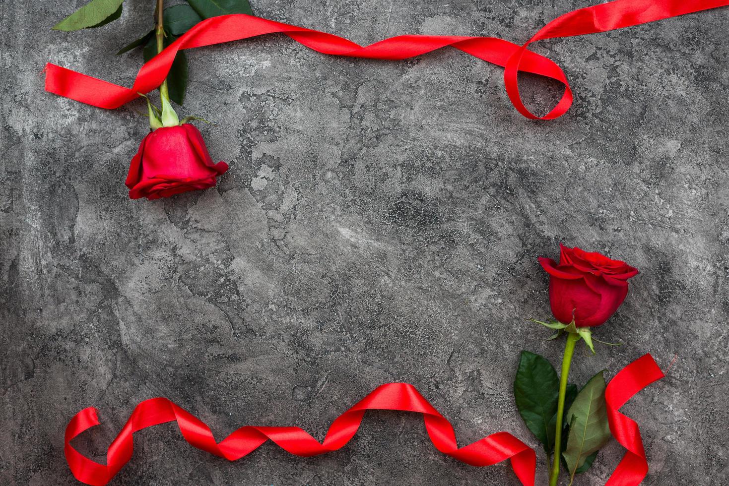 Valentine's Day or other love holiday. On a gray background, red trojans are decorated with red ribbon, top view photo