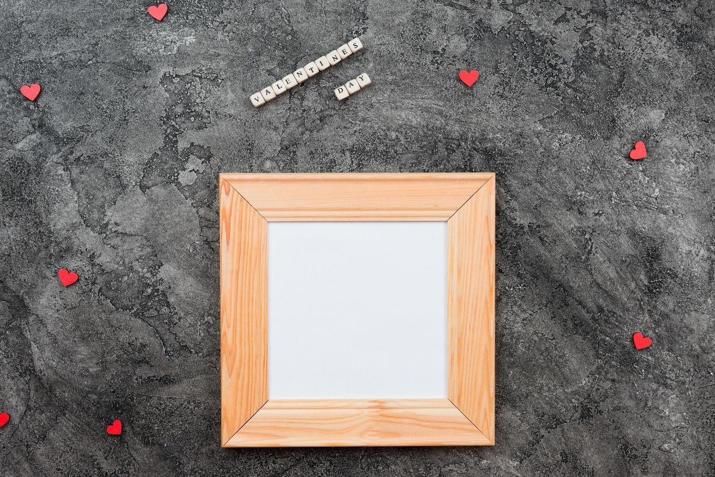 On a dark gray background lies a wooden frame, with space for writing wishes, copy space photo