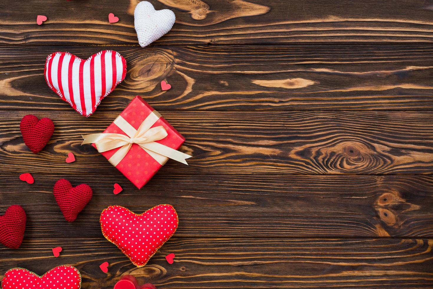 tema de amor, corazones textiles dispuestos sobre una superficie de madera, una caja de regalo para el día de San Valentín foto
