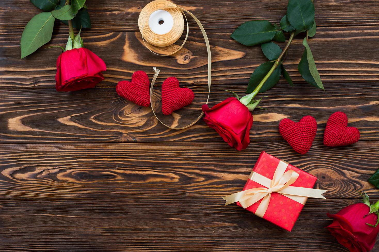 Valentine or other holiday handmade present with red hearts and gifts box in holiday wrapper. Present box decoration of gift on wooden table top view with copy space, empty space for design. photo