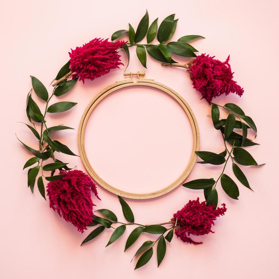 Closeup a circle of fresh flowers  and a green leafs lie on a pink background -  Copy space photo