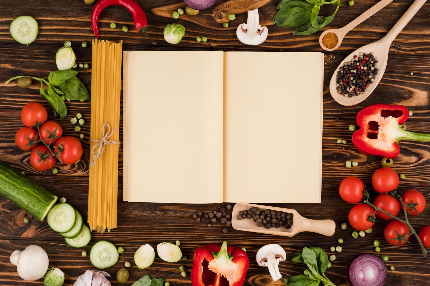 un libro de recetas se abre sobre una mesa de madera, con ingredientes para platos italianos dispuestos foto