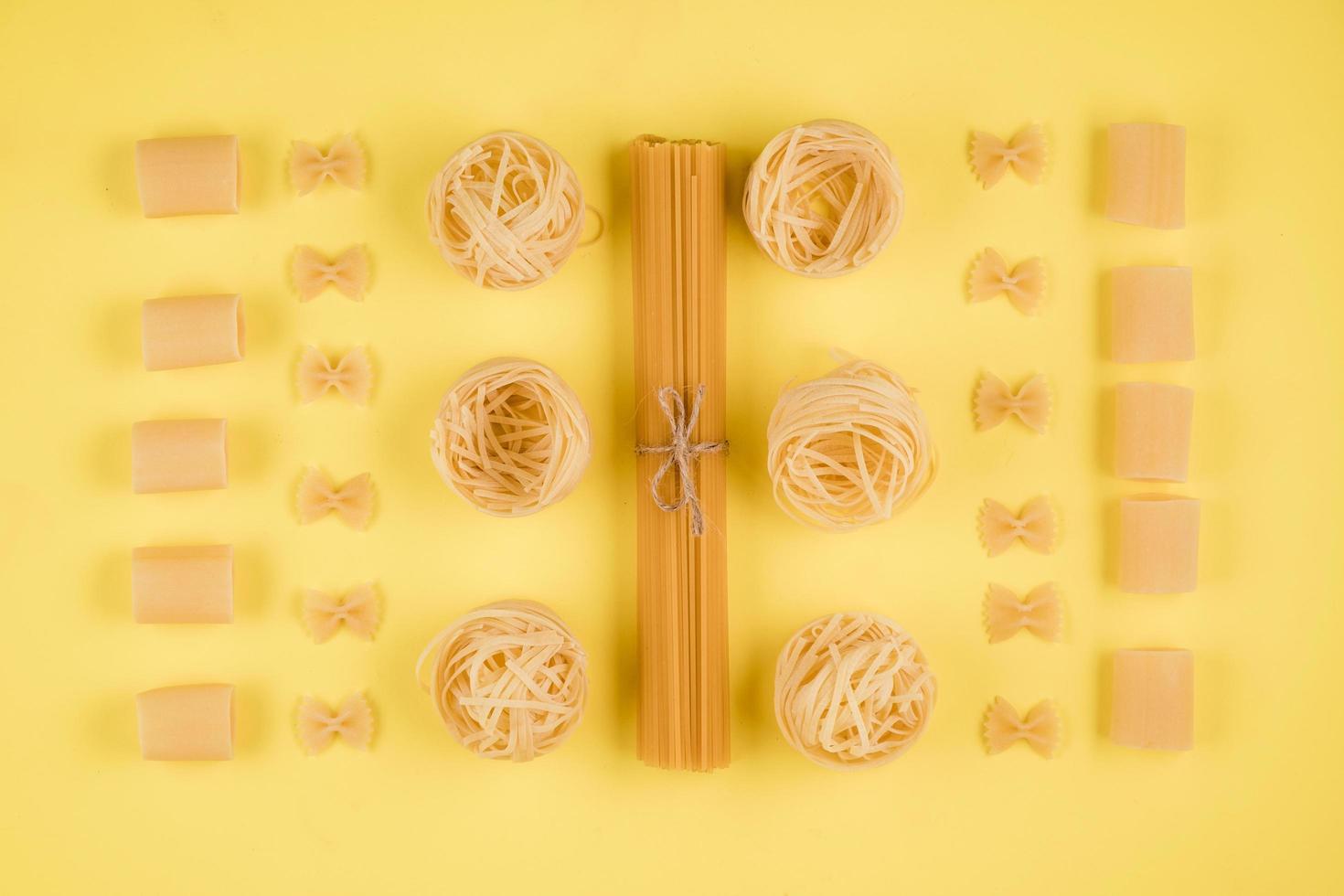 Assorted types of pasta on yellow background. Various forms of pasta. photo